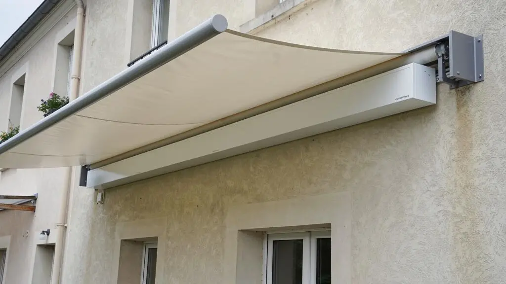 Store banne de 6 mètres déployé sur une façade résidentielle montrant l'encombrement complet du coffre et de la toile